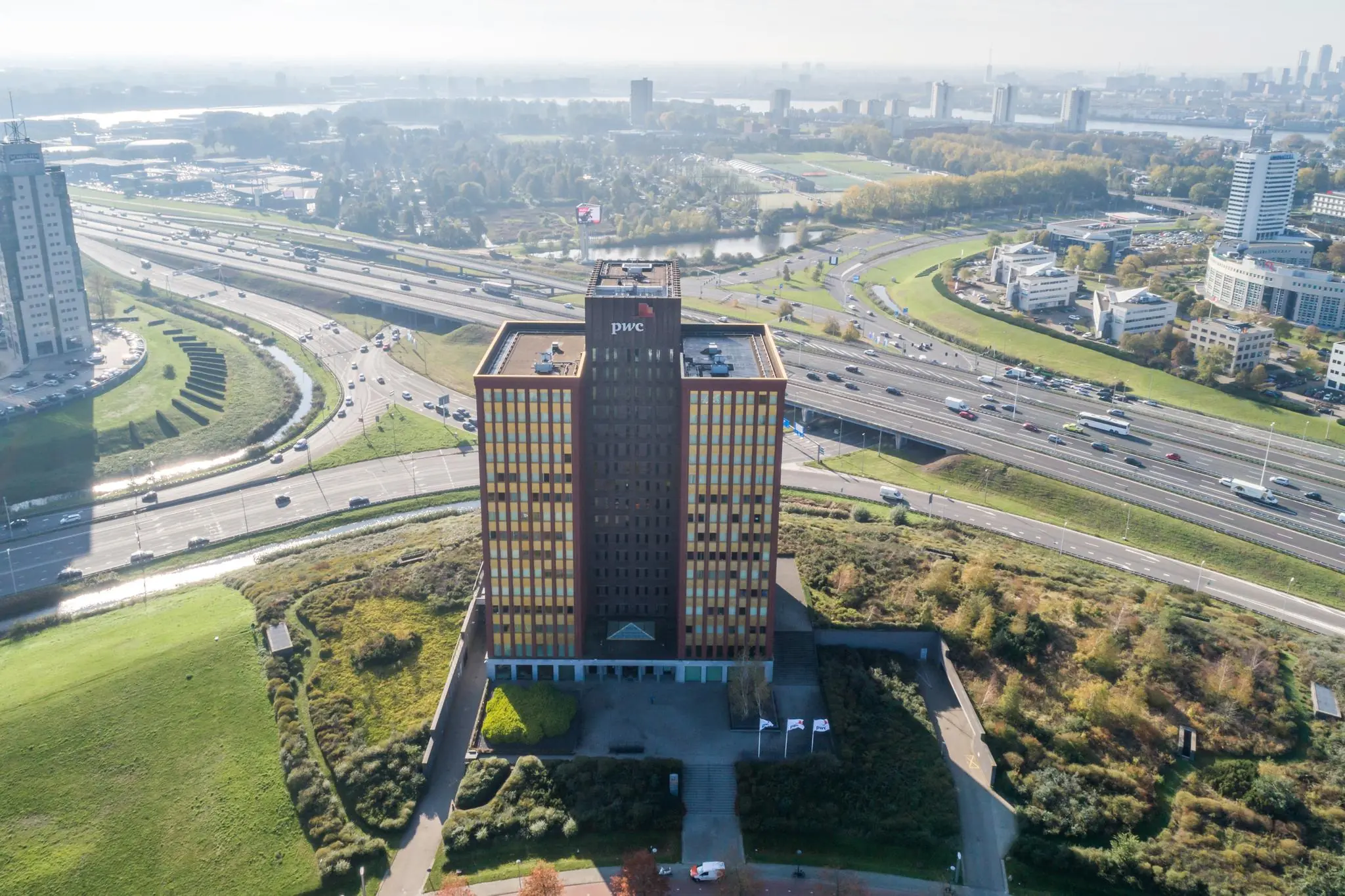 Luchtfoto van het PwC-kantoor aan de Fascinatio Boulevard in Rotterdam, omringd door snelwegen en groen.